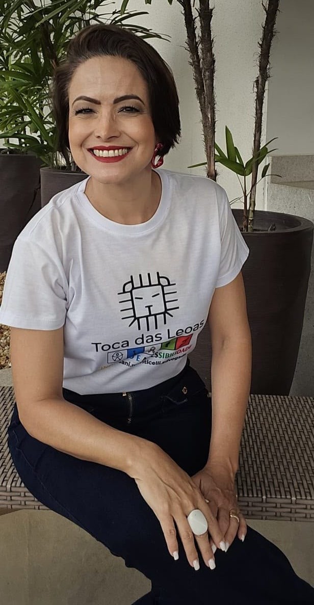 Daniella Monticelli sentada, sorrindo, com a camiseta da Toca das Leoas